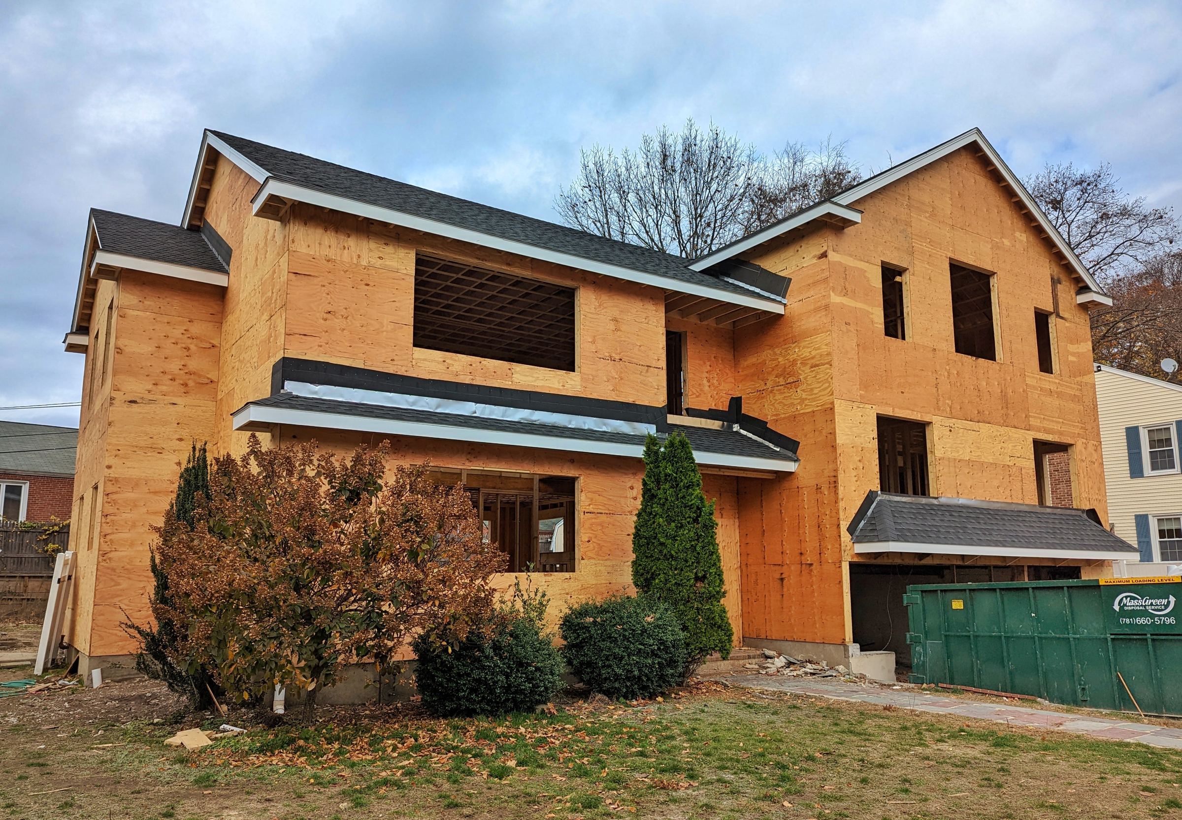 Two-story infill home under construction with new roof and sheathing
