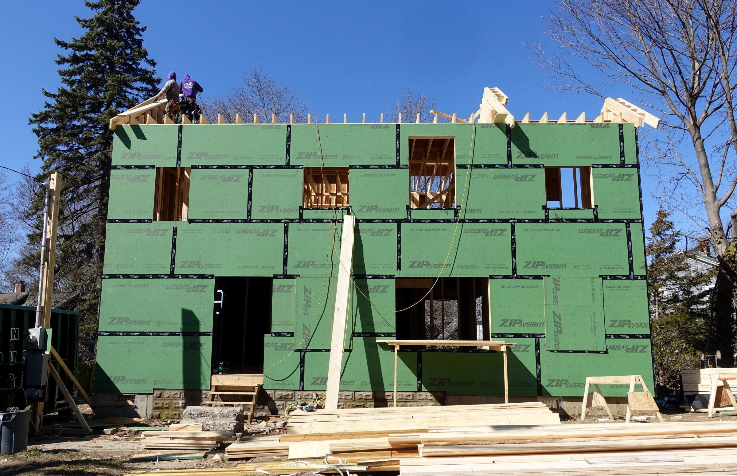 Framing crew working on the roof of a new home under a clear blue sky